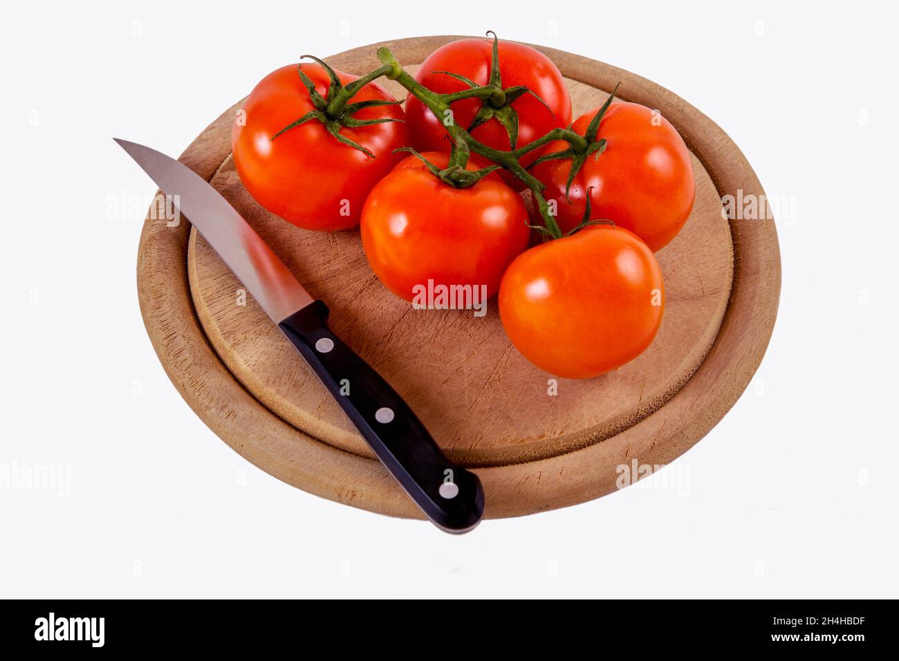 Fresh tomatoes on a round kitchen board isolated on a white background Stock Photo