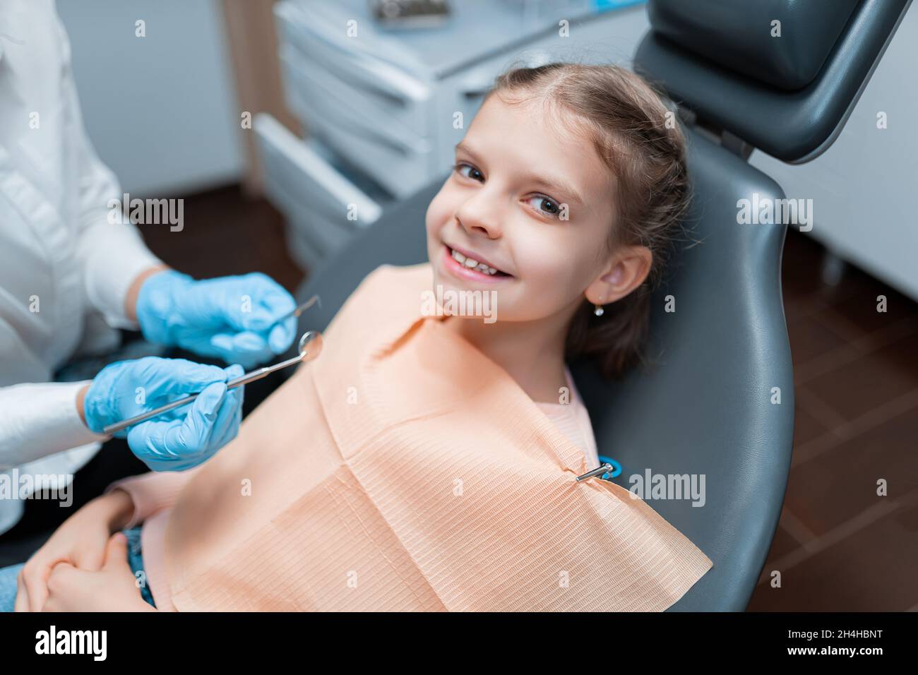 Cute little girl visiting dentist, having his teeth checked by