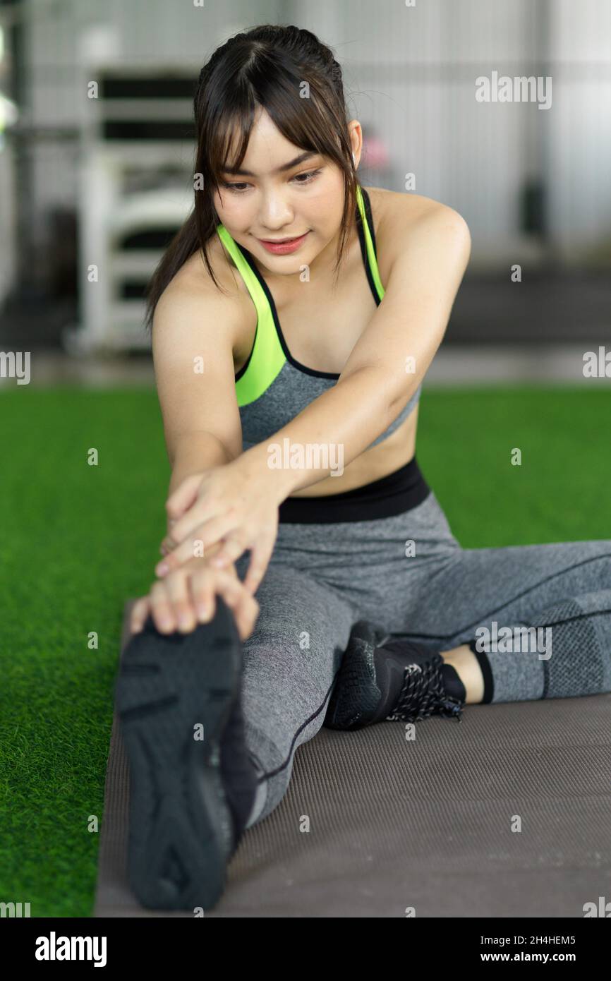 Sport and recreation concept. Woman in sportswear doing legs stretching to ready for exercise bodyweight training. Stock Photo
