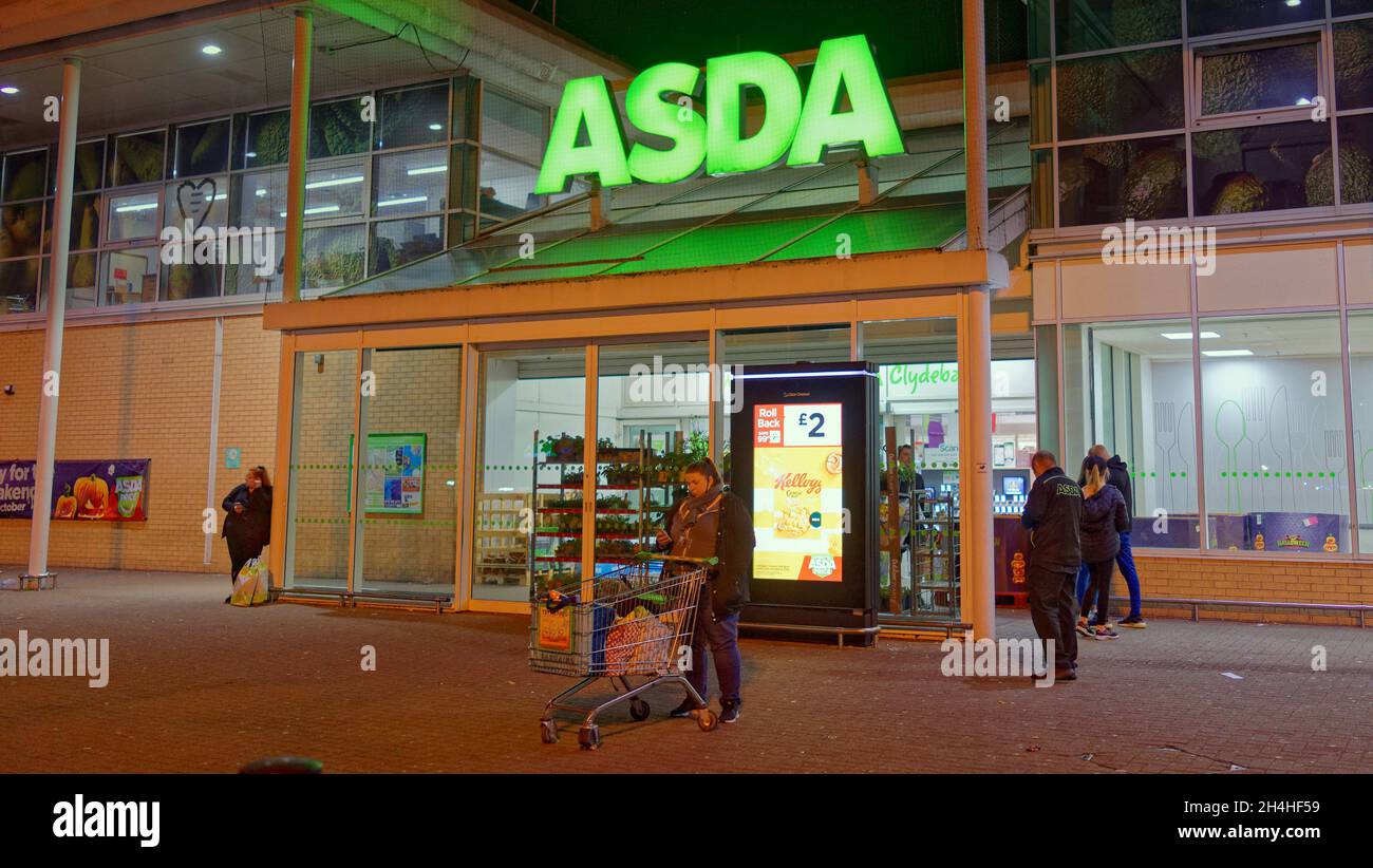 Asda 24 hour late night opening shopping trolly customer at night in