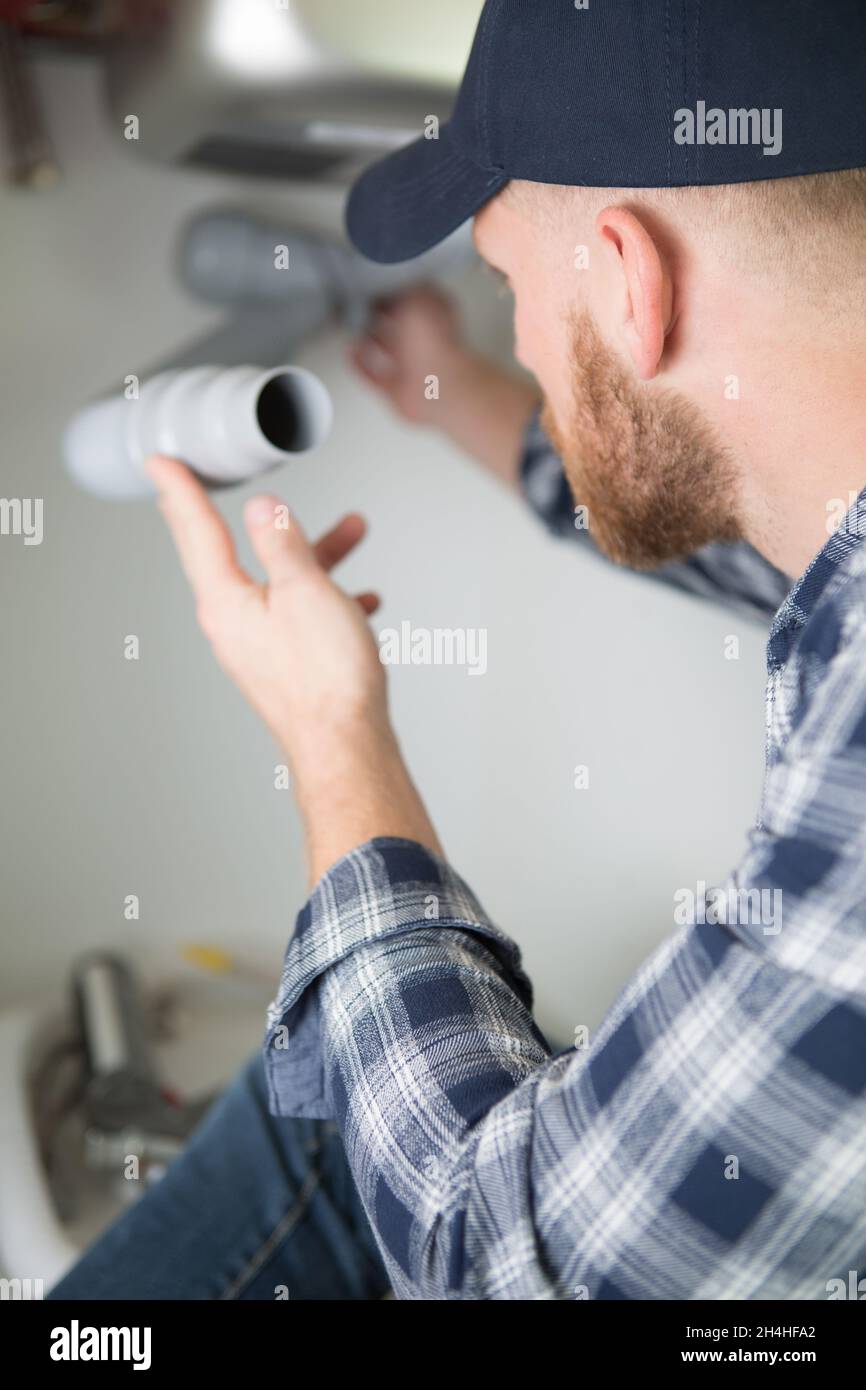 young man fixing a leaking pipe under the sink Stock Photo Alamy