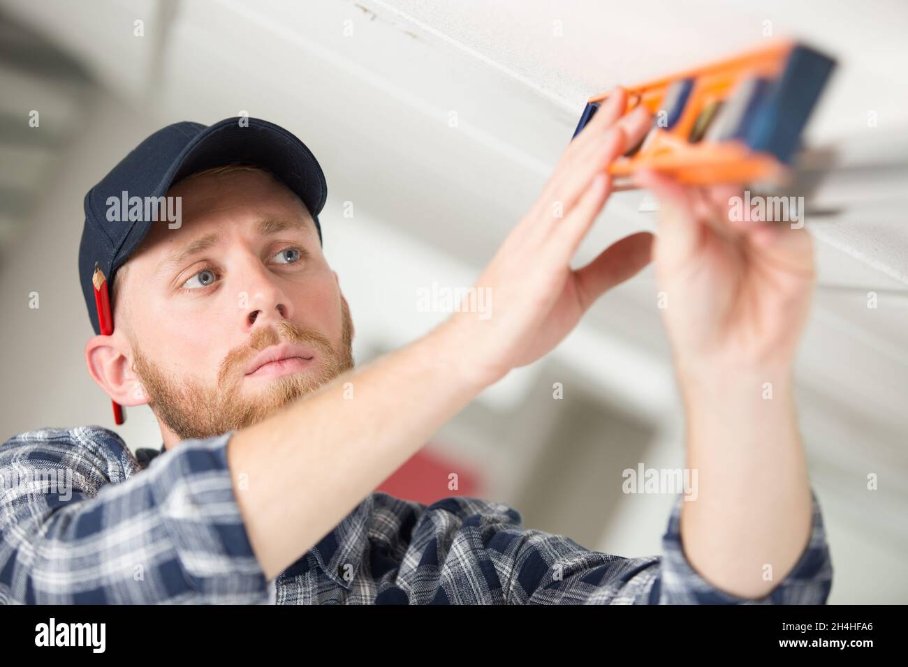 worker taking ceiling measures with spirit level Stock Photo
