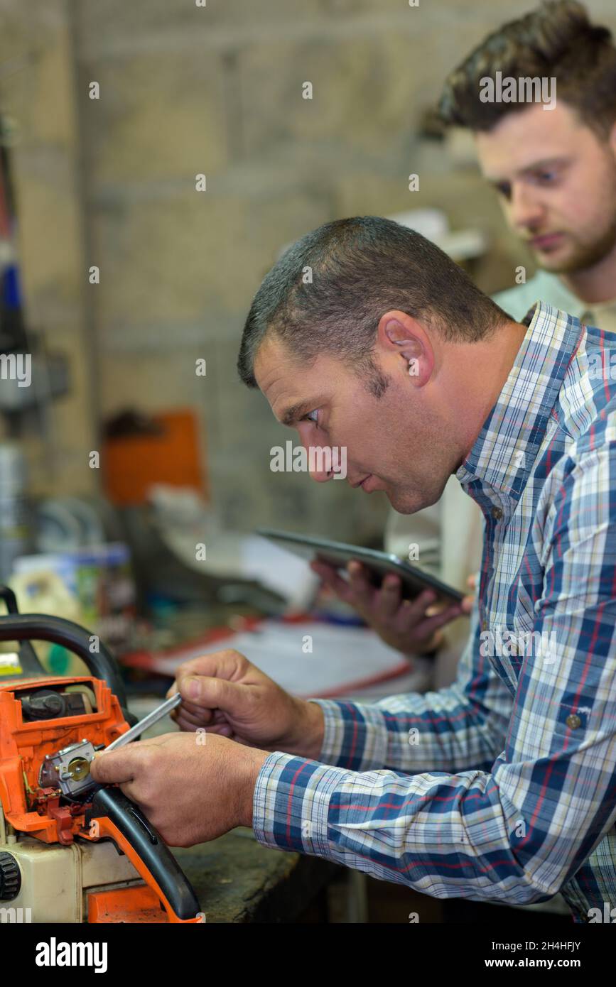engineer and apprentice working on machine in factory Stock Photo