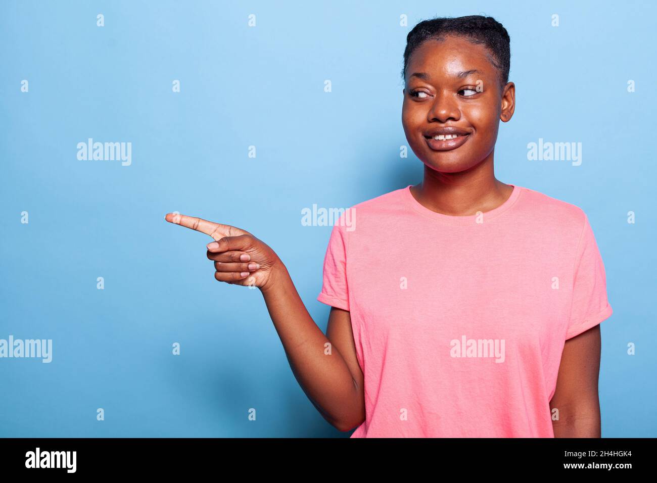 Portrait of smiling african american young woman pointing finger at ...