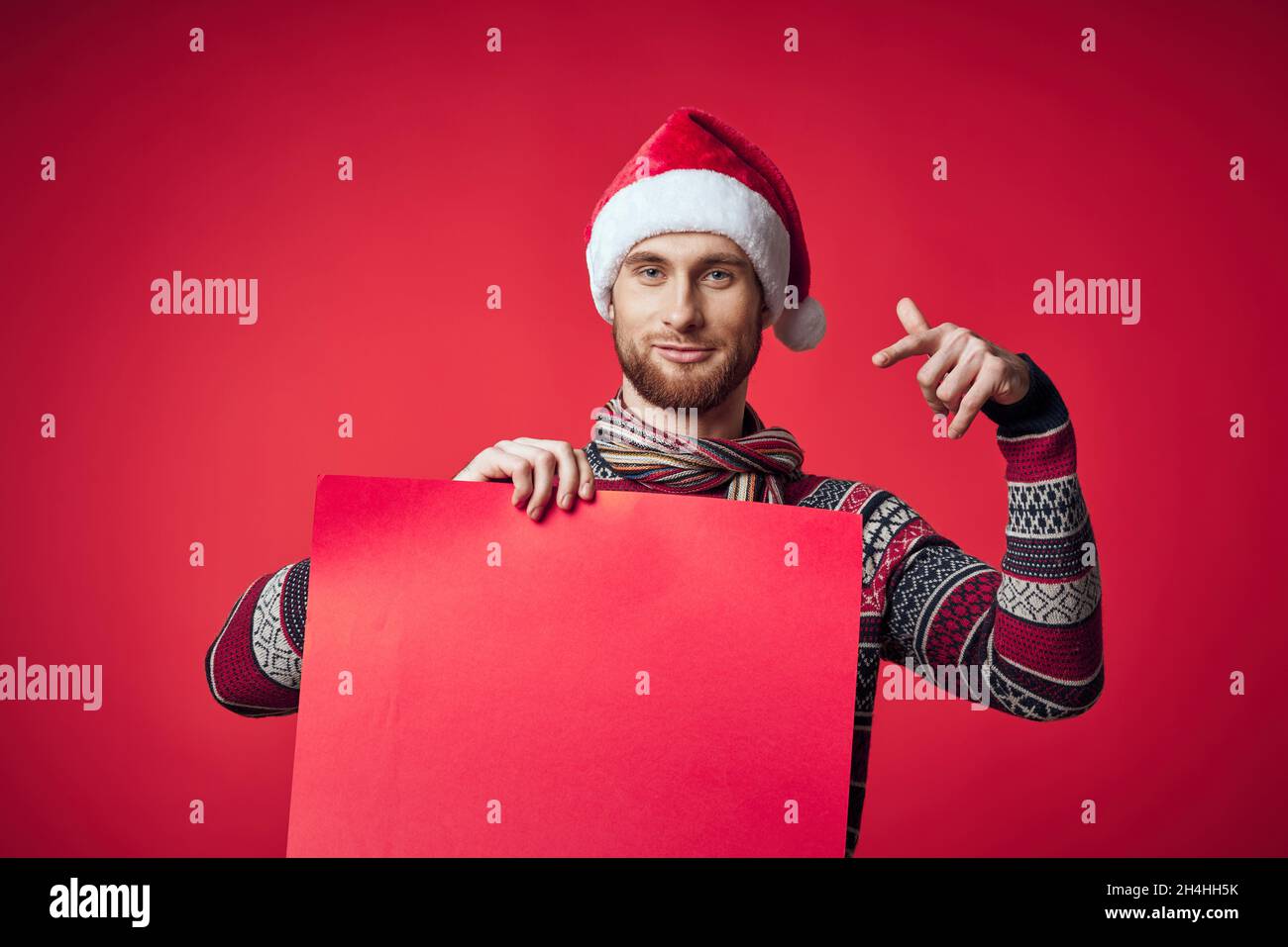 emotional man in a santa hat holding a banner holiday red background ...