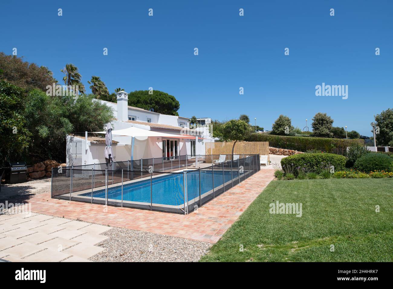 Exterior of luxury villa with garden and fenced swimming pool Stock Photo