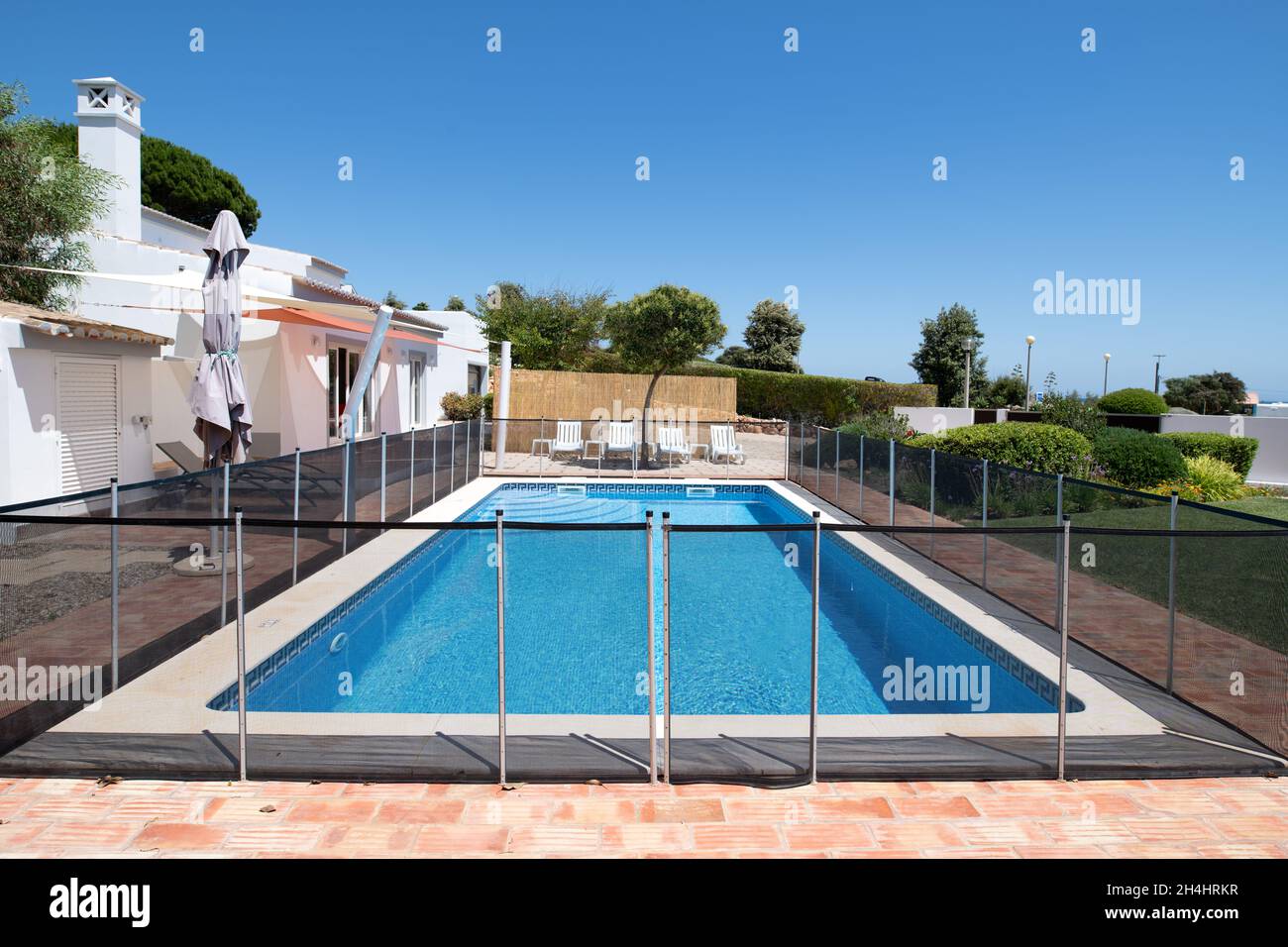 Fenced swimming pool in the garden of a luxury holiday villa Stock Photo