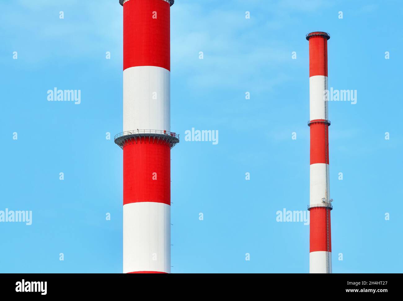 Close up picture of red and white painted chimneys against the blue sky. Stock Photo