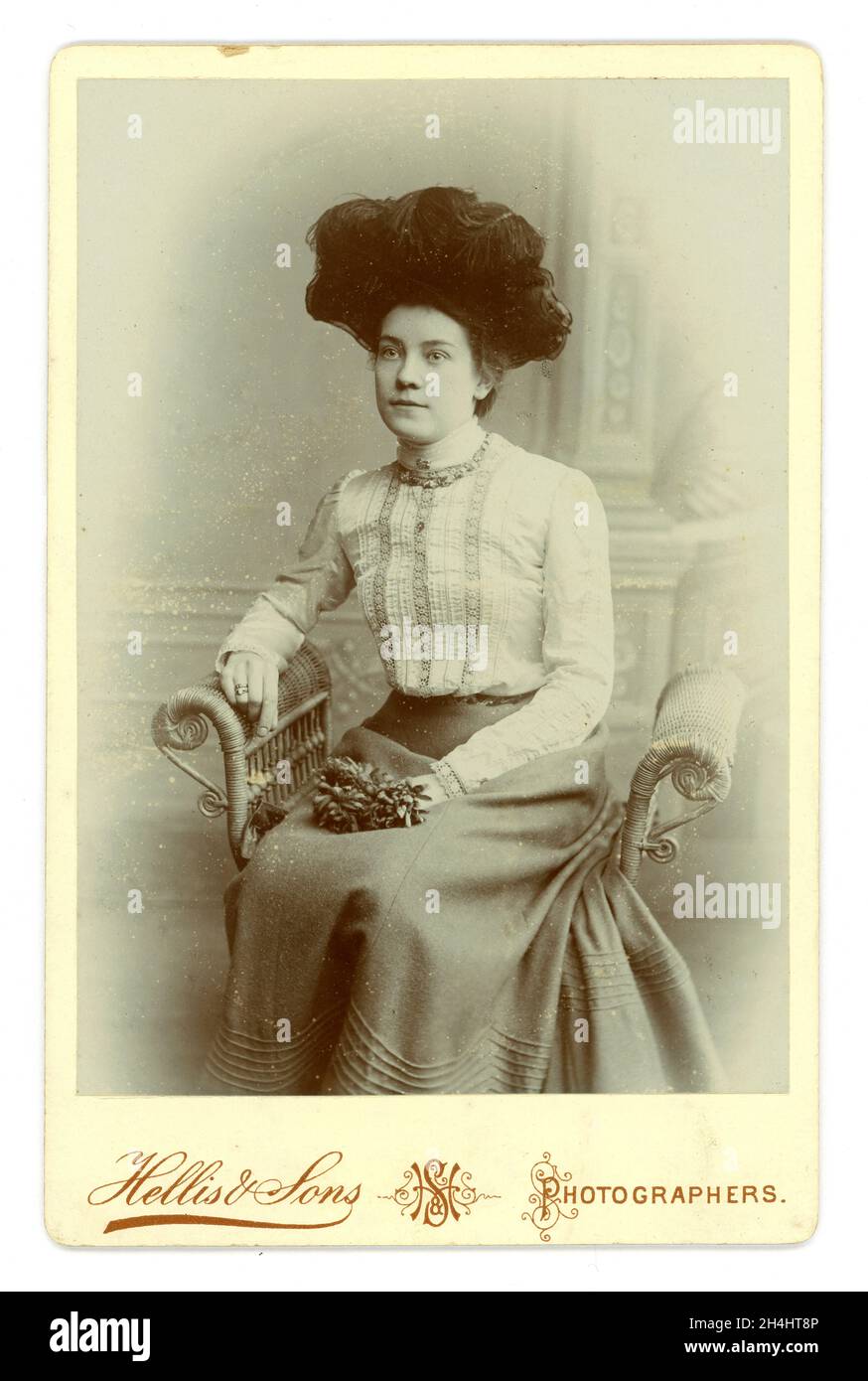 Original late Victorian or early Edwardian cabinet card of pretty young woman wearing a hat with black ostrich feathers, high neck blouse, full skirt, by Hellis & Sons, London, U.K.  circa 1900 or 1901 Stock Photo