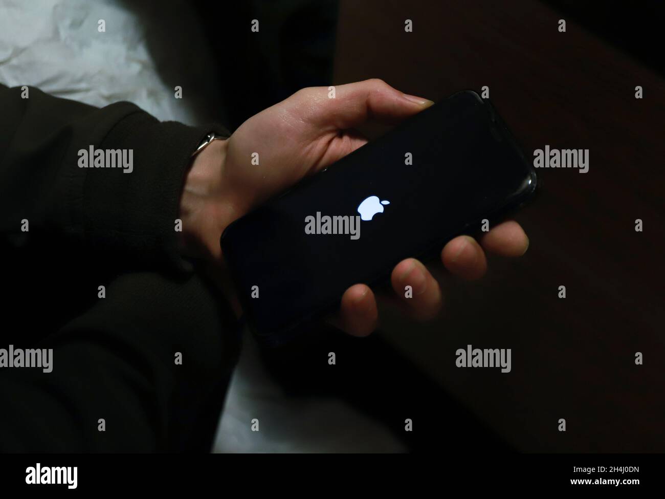 Hand with Apple iPhone Black Screen with bright Apple logo Stock Photo