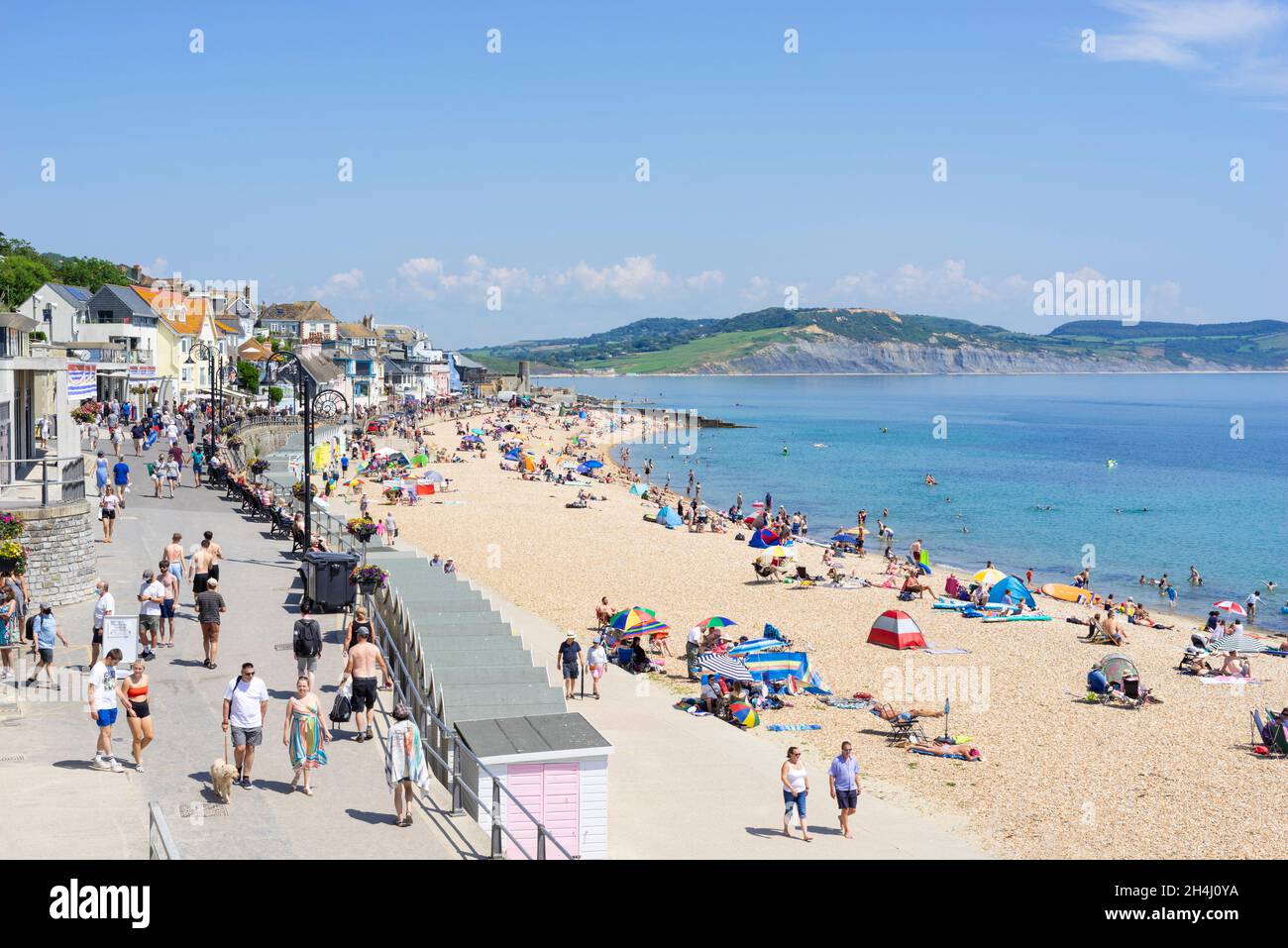 Families on the beach with pop up beach tents deckchairs beach umbrellas and paddle boards on Sandy beach at Lyme Regis Dorset England UK GB Europe Stock Photo
