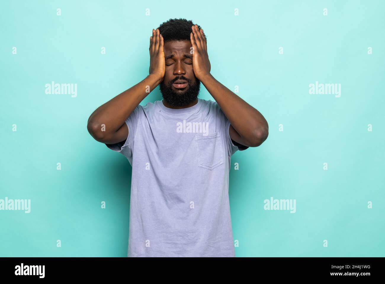 Scared panicking black skin man holding head with two hands isolated on vivid cyan colored background Stock Photo