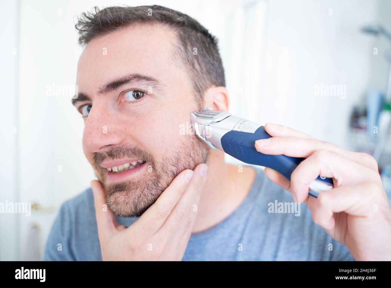 Man shaving his beard holding electric beard trimmer Stock Photo Alamy