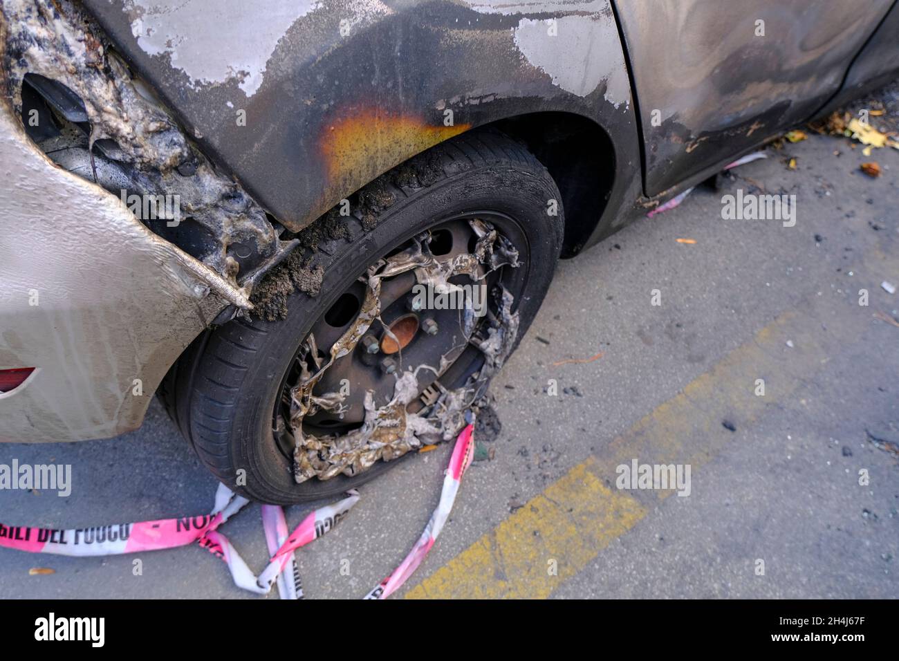 Broken and burnt wheel of the car close-up. Riot, civil protest, hooliganism, criminal in the city. Stock Photo