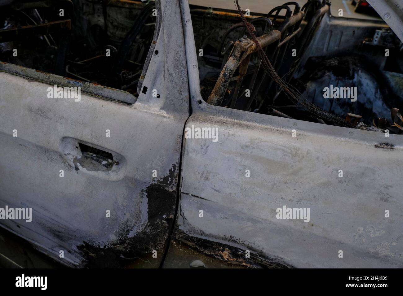 Burnt car's door in the street close-up. Riot, civil protest, hooliganism, criminal in the city. Explosion, fire result. Car insurance concept Stock Photo