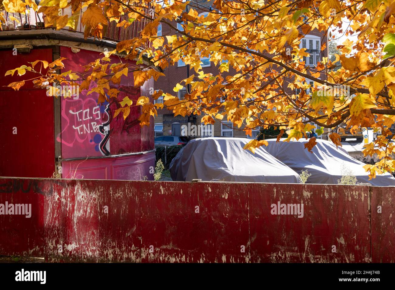 Two stored cars are parked under shiny covers on private property, a derelict Whitechapel pub in the East End, on 2nd November 2021, in London, England. Stock Photo
