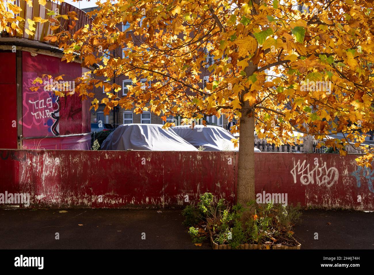 Two stored cars are parked under shiny covers on private property, a derelict Whitechapel pub in the East End, on 2nd November 2021, in London, England. Stock Photo
