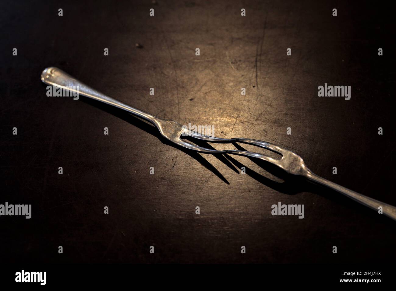 Two forks touching at tines under spotlight. Stock Photo
