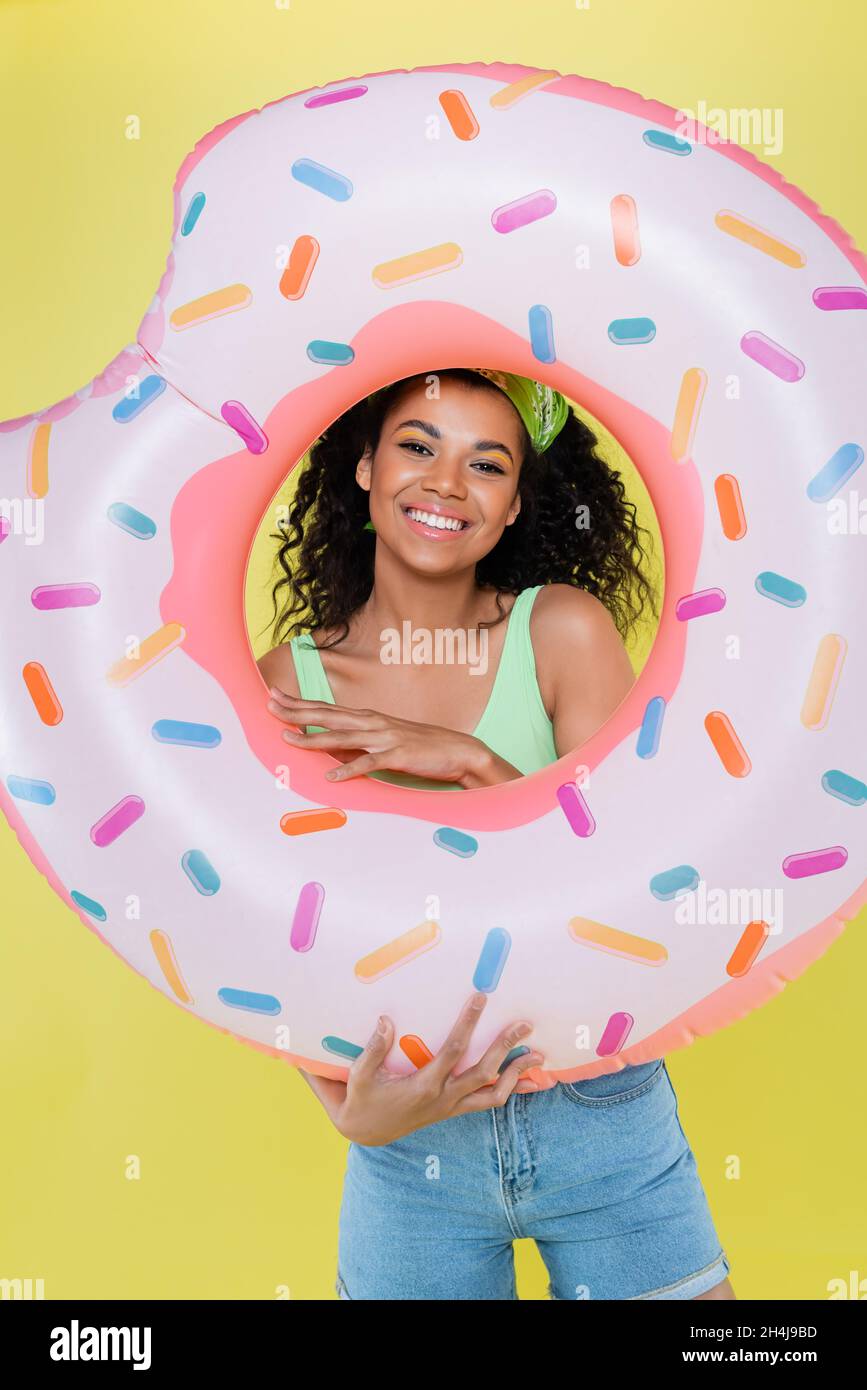 happy african american young woman holding inflatable ring isolated on yellow Stock Photo