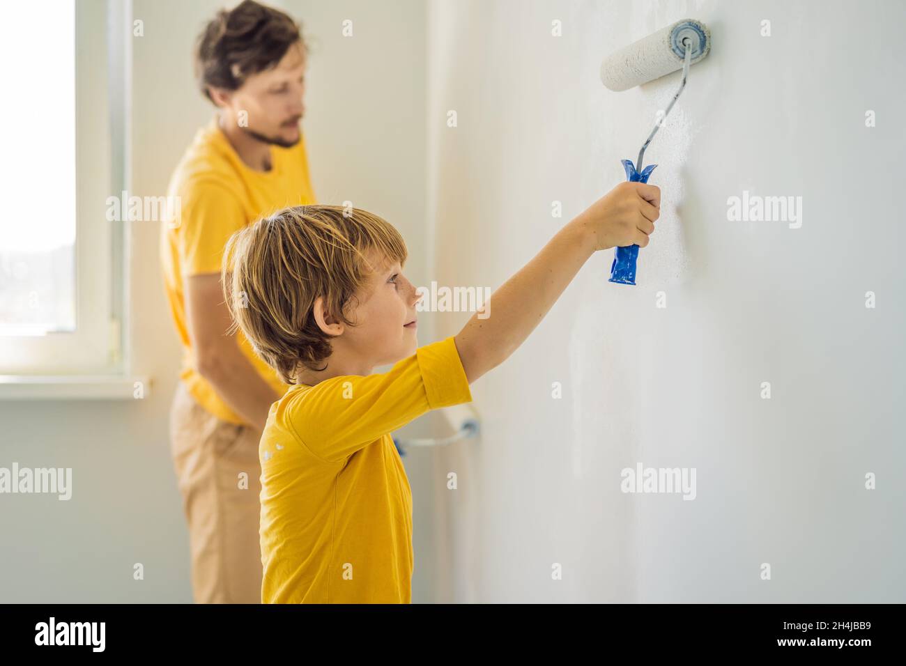 Father and son painting a wall in their home do it in the course of ...