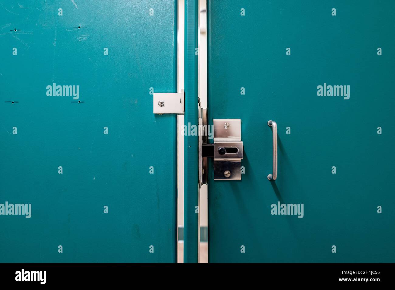 Generic metal public bathroom stall latch closed with the door gap