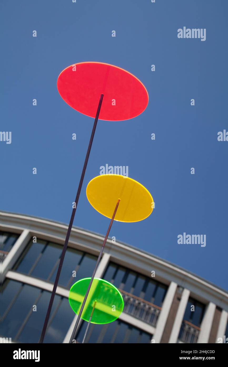 red, green and yellow light discs in front of parts of a building with blue sky Stock Photo