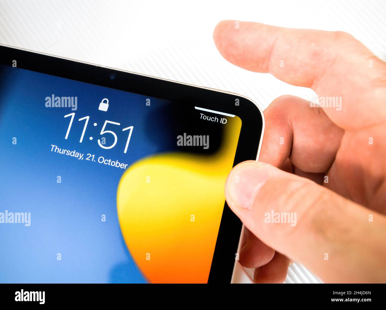 Touch ID message as man trying to unlock with the fingertip the new iPad Mini 6th tablet Stock Photo