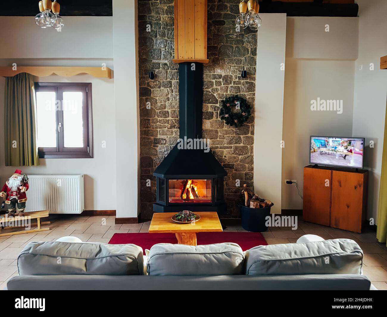Warm cosy fireplace in mountain chalet with real firewood burning. Cozy winter concept. Winter vacation Stock Photo