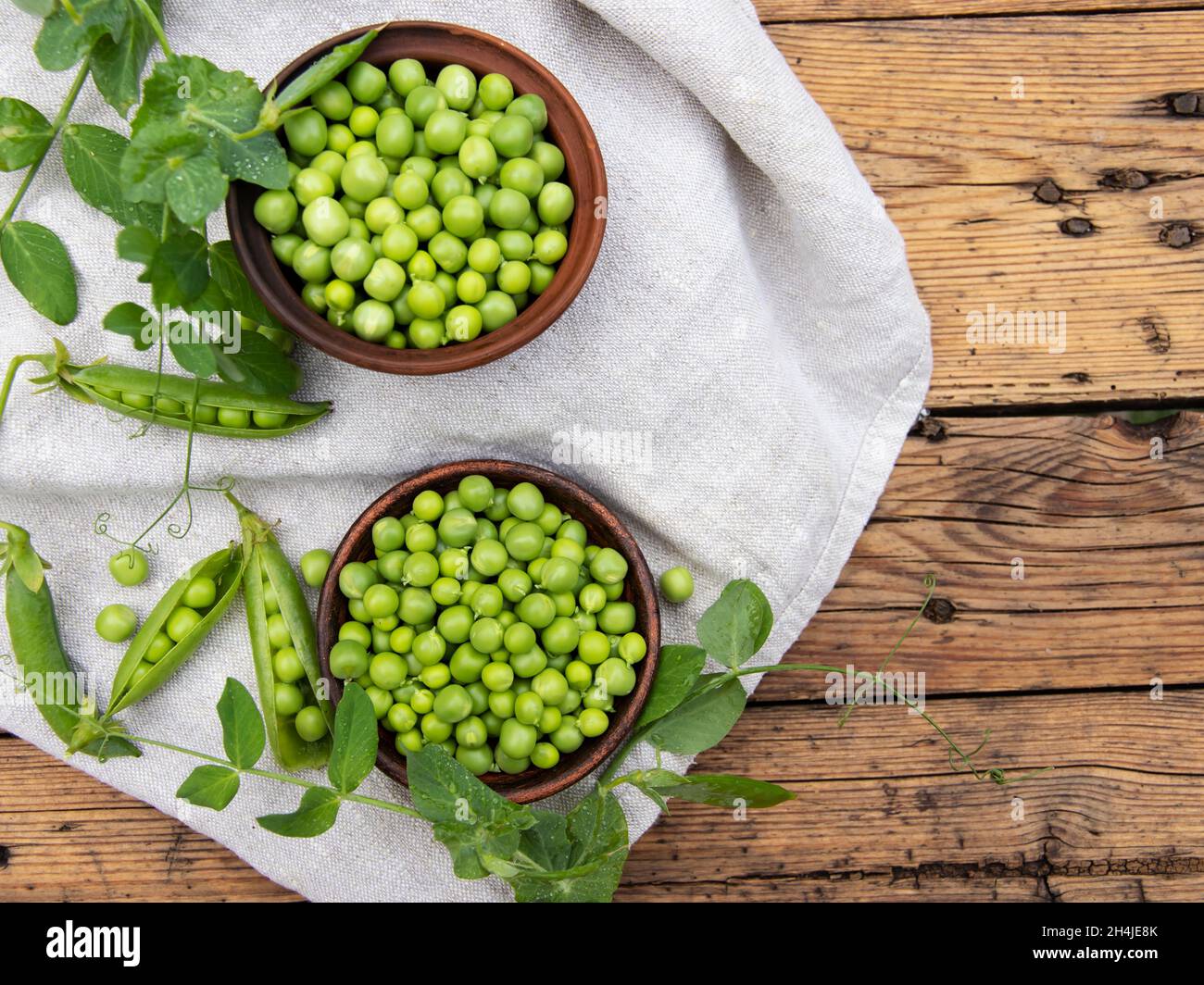 Fresh green peas young in bowl, on wood table, close up, seeds, pods, sprouts. Stock Photo