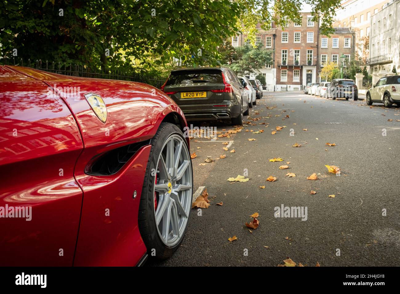 London- Red Ferrari parked on upmarket street of luxury houses in Kensington Stock Photo