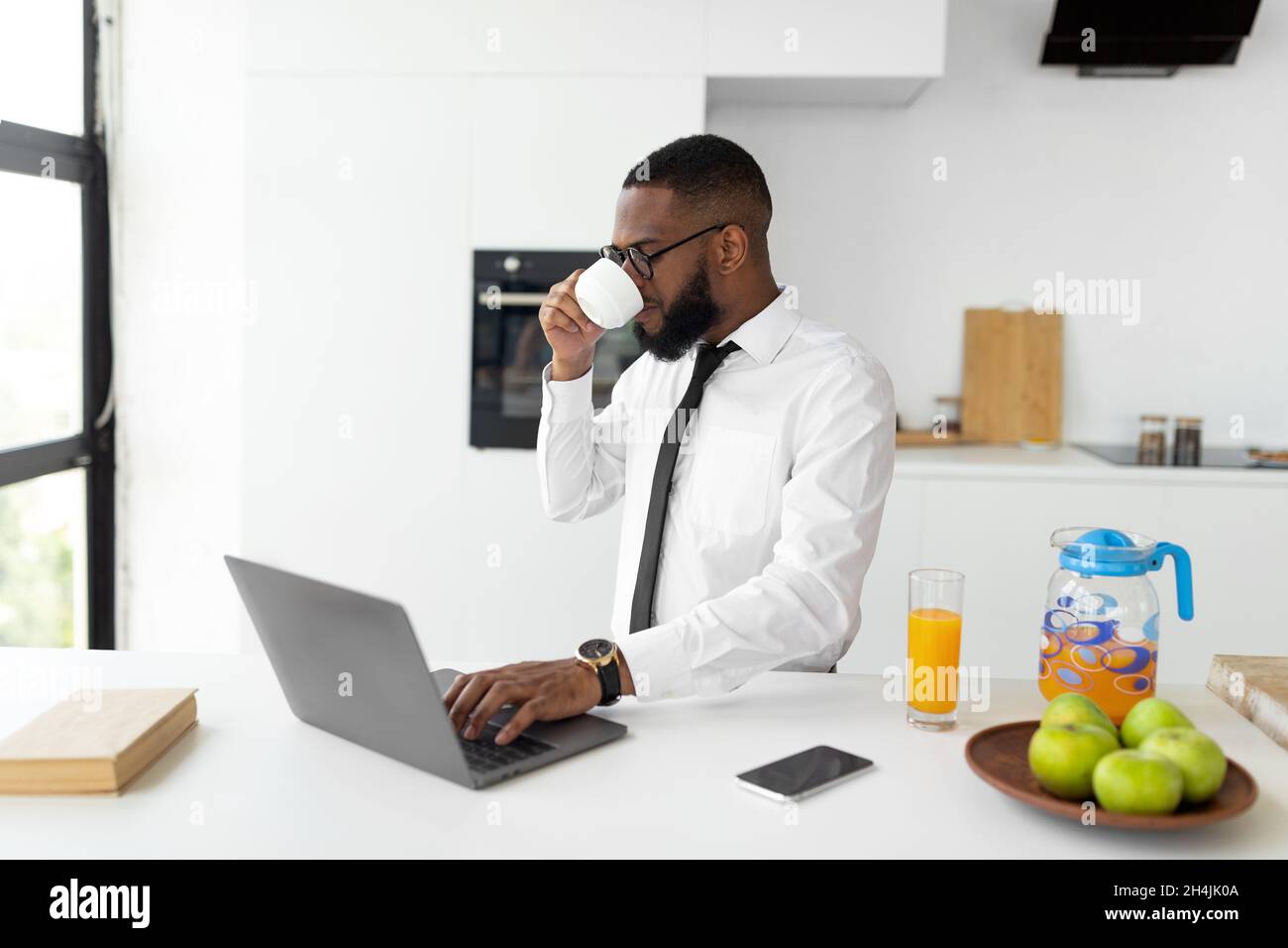 African American man using laptop drinking coffee Stock Photo