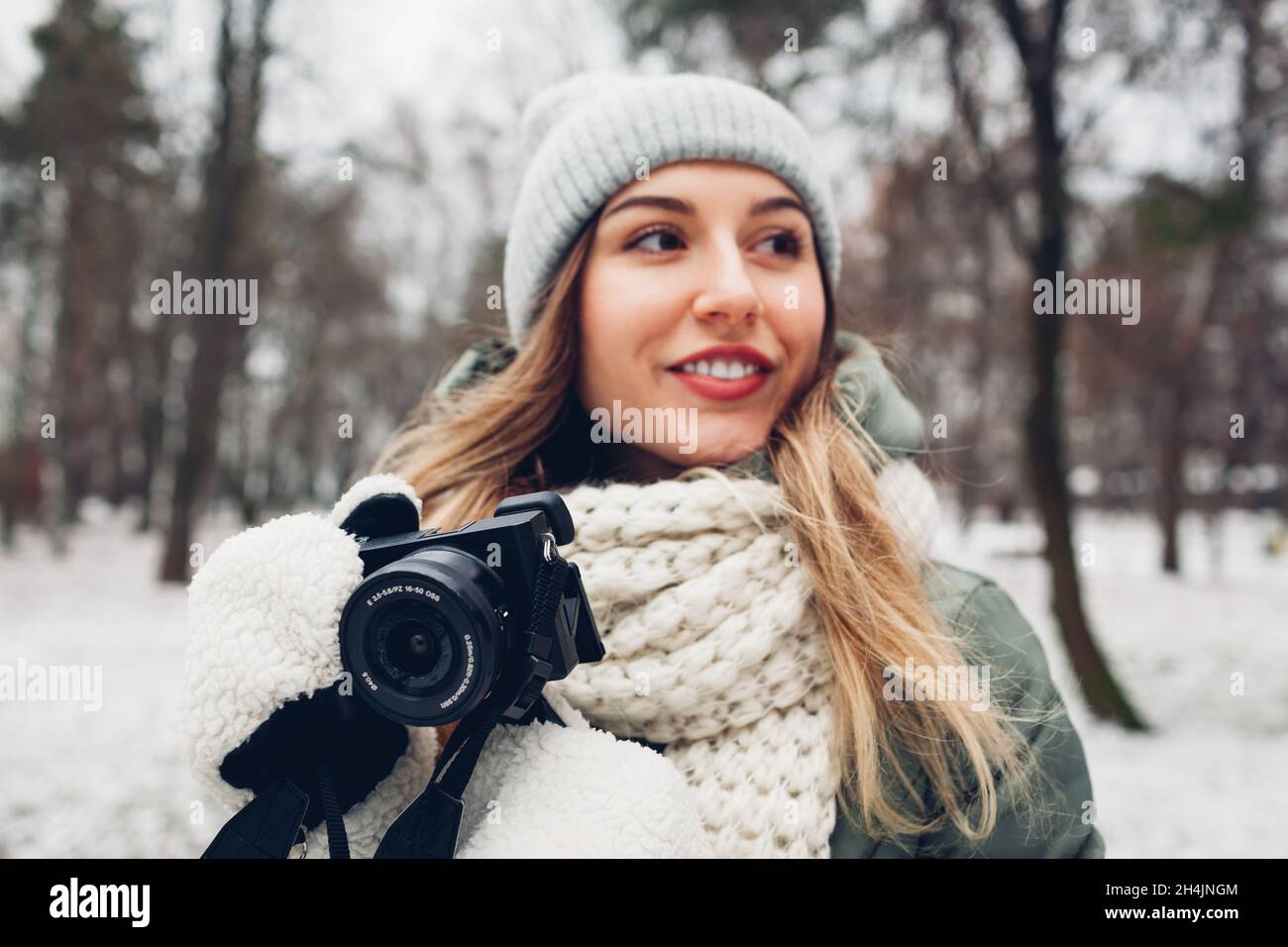 Woman photographer takes pictures of snowy winter park using camera