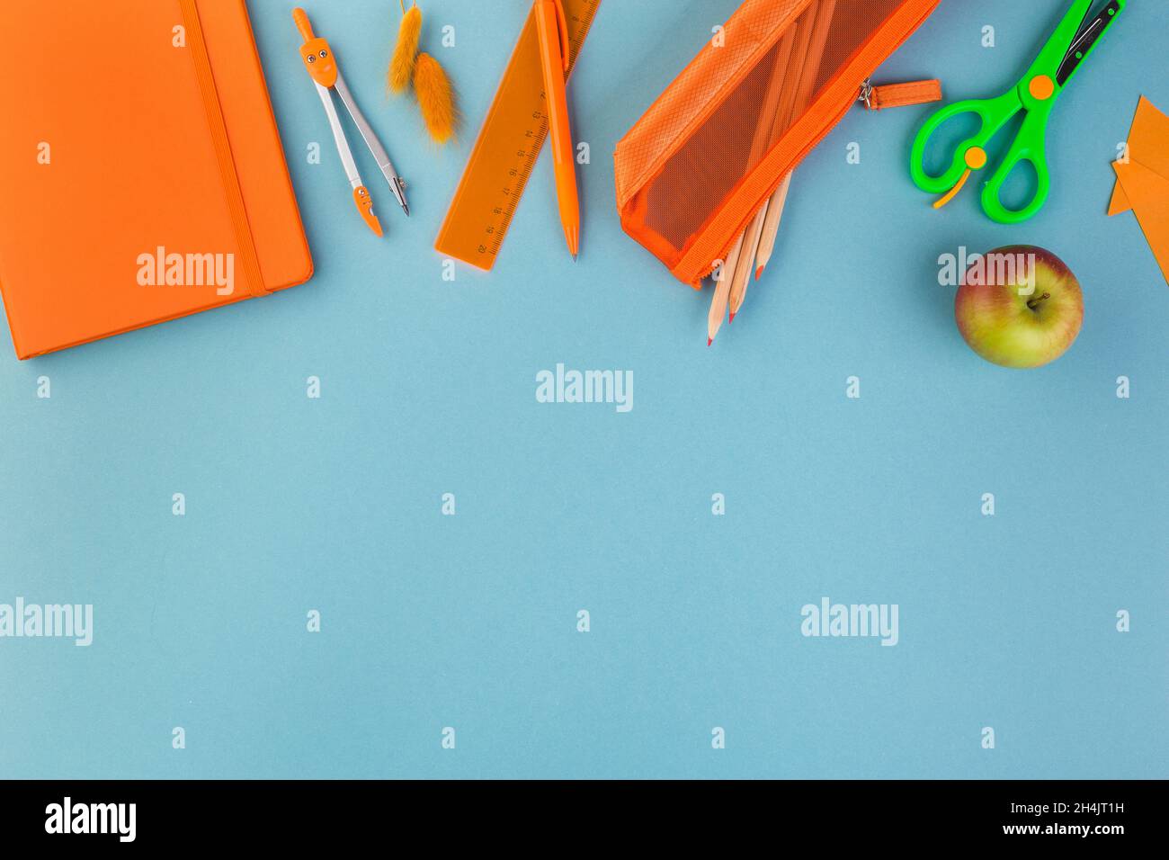 Creative, fashionable, minimalistic, school or office workspace with orange supplies on blue background. Flat lay. Stock Photo