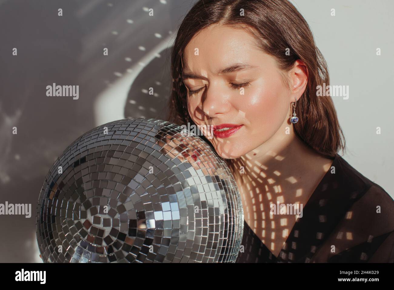 Portrait of a woman with closed eyes holding a glitter ball Stock Photo