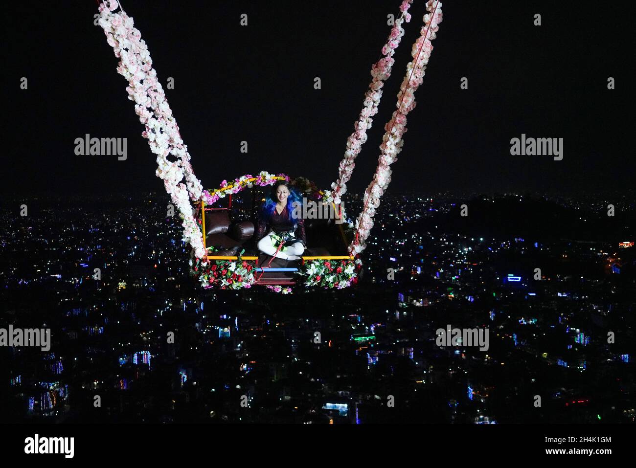 November 3, 2021, Kathmandu, Nepal A woman plays on a swing with city