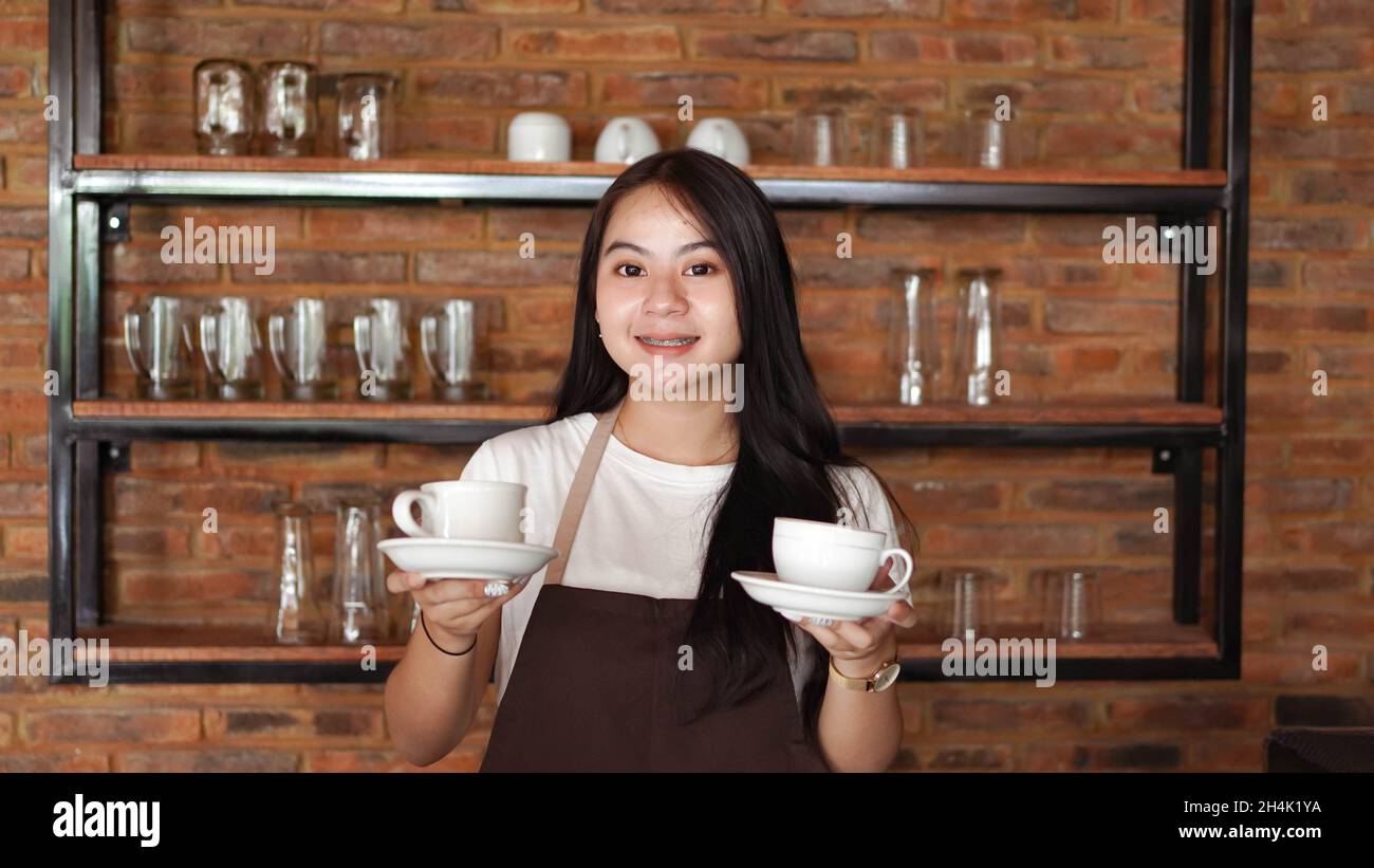 Smiling barista holding two coffee cups Stock Photo