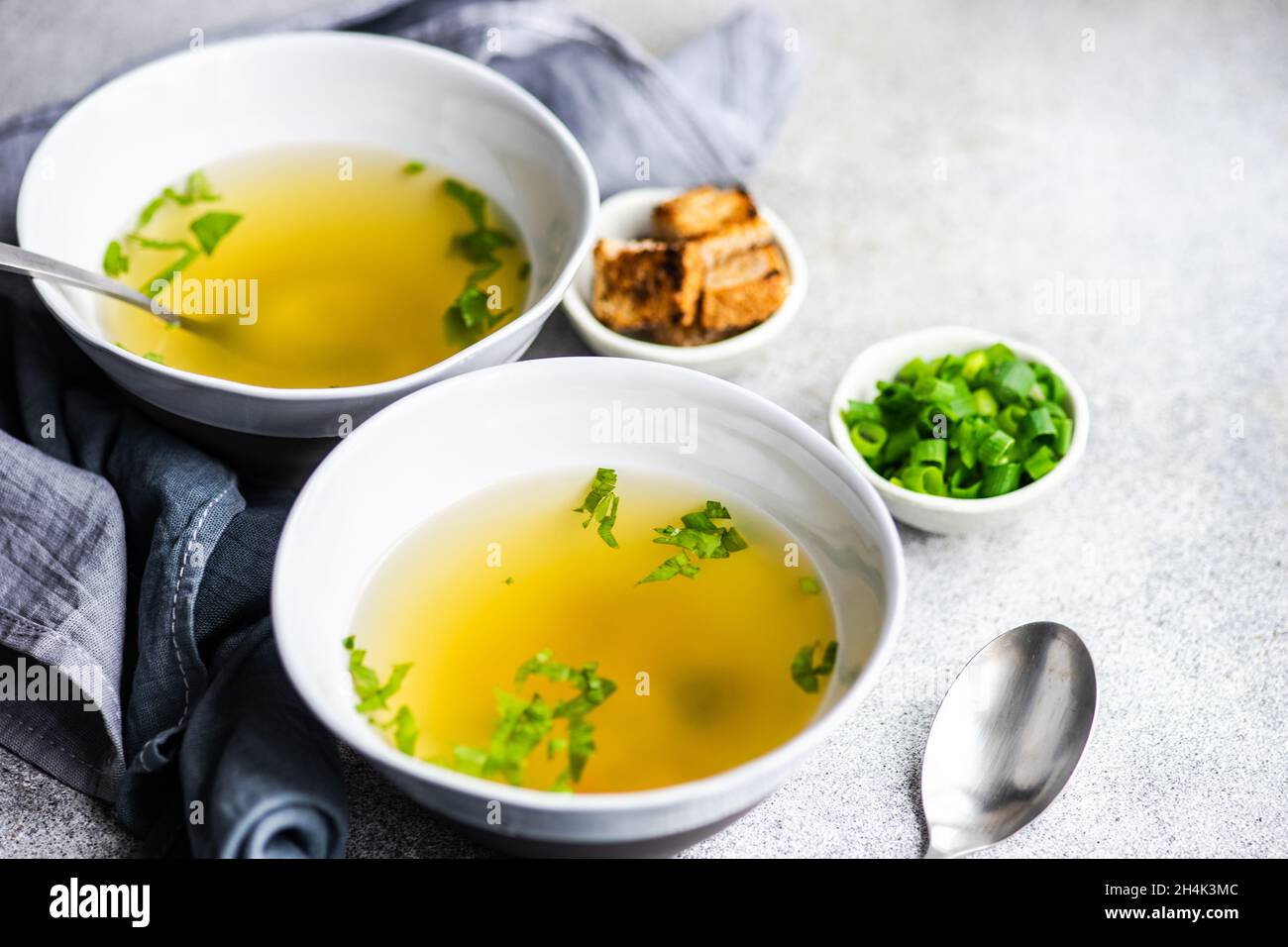 Two bowls of healthy chicken broth with croutons, parsley and spring onions Stock Photo