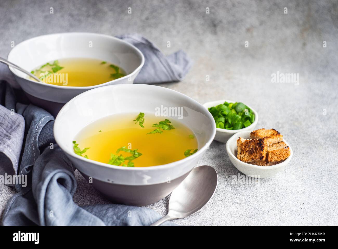 Two bowls of healthy chicken broth with croutons, parsley and spring onions Stock Photo