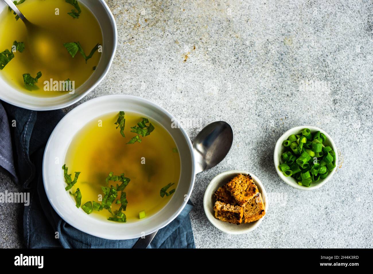 Two bowls of healthy chicken broth with pasta, croutons, parsley and spring onions Stock Photo