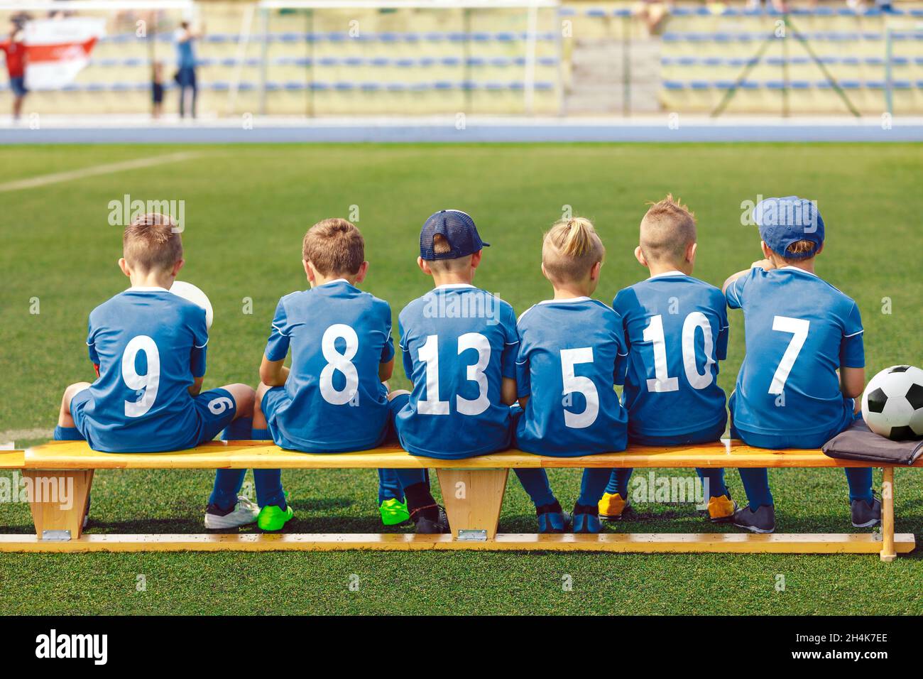 School Boys in Sports Football Team. Kids is Classic Blue Soccer Jersey Uniforms With Numbers. Kids Playing Sports Together. Children Sitting on Sidel Stock Photo