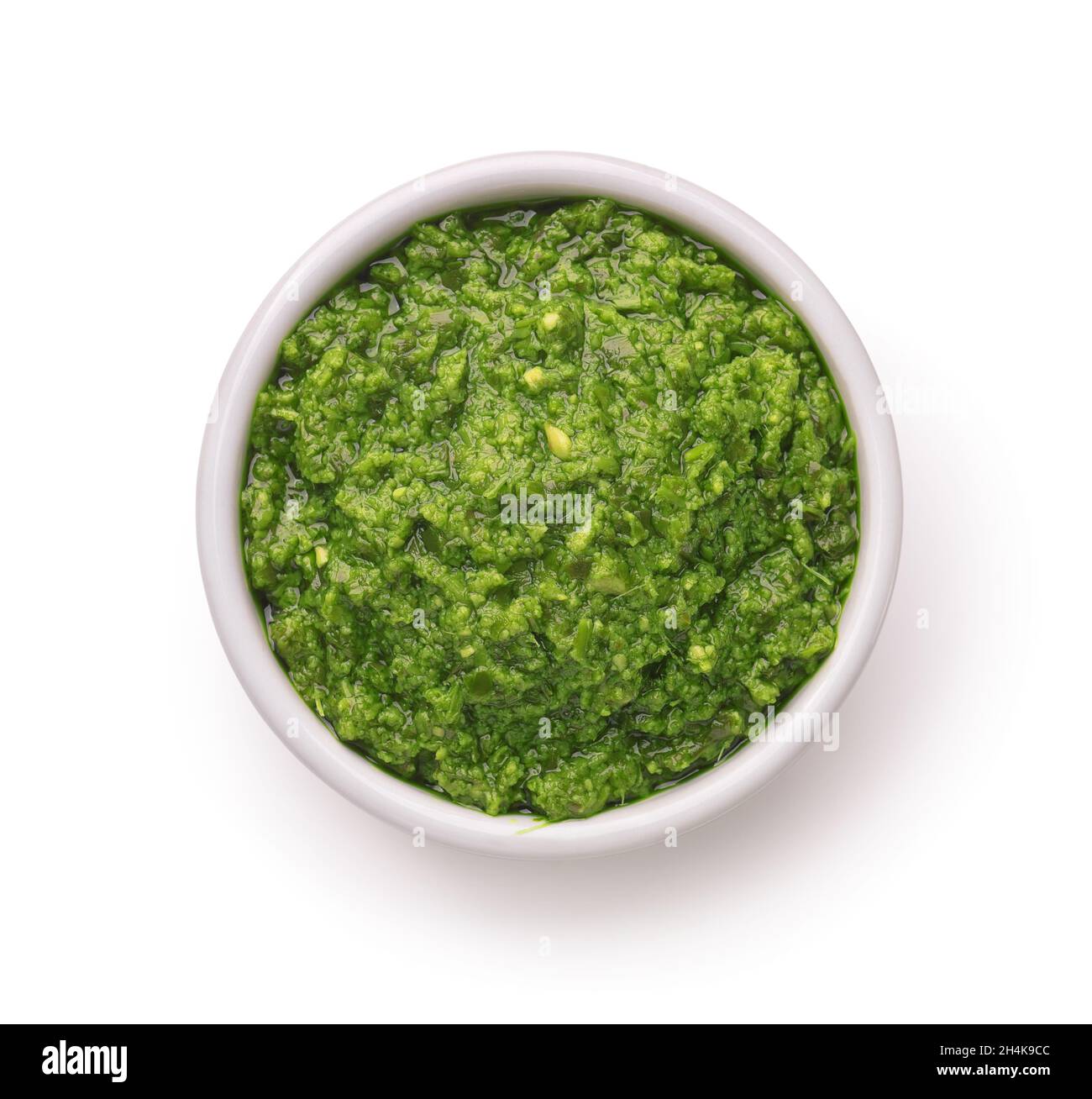 Top view of green pesto sauce in ceramic cup isolated on white Stock Photo