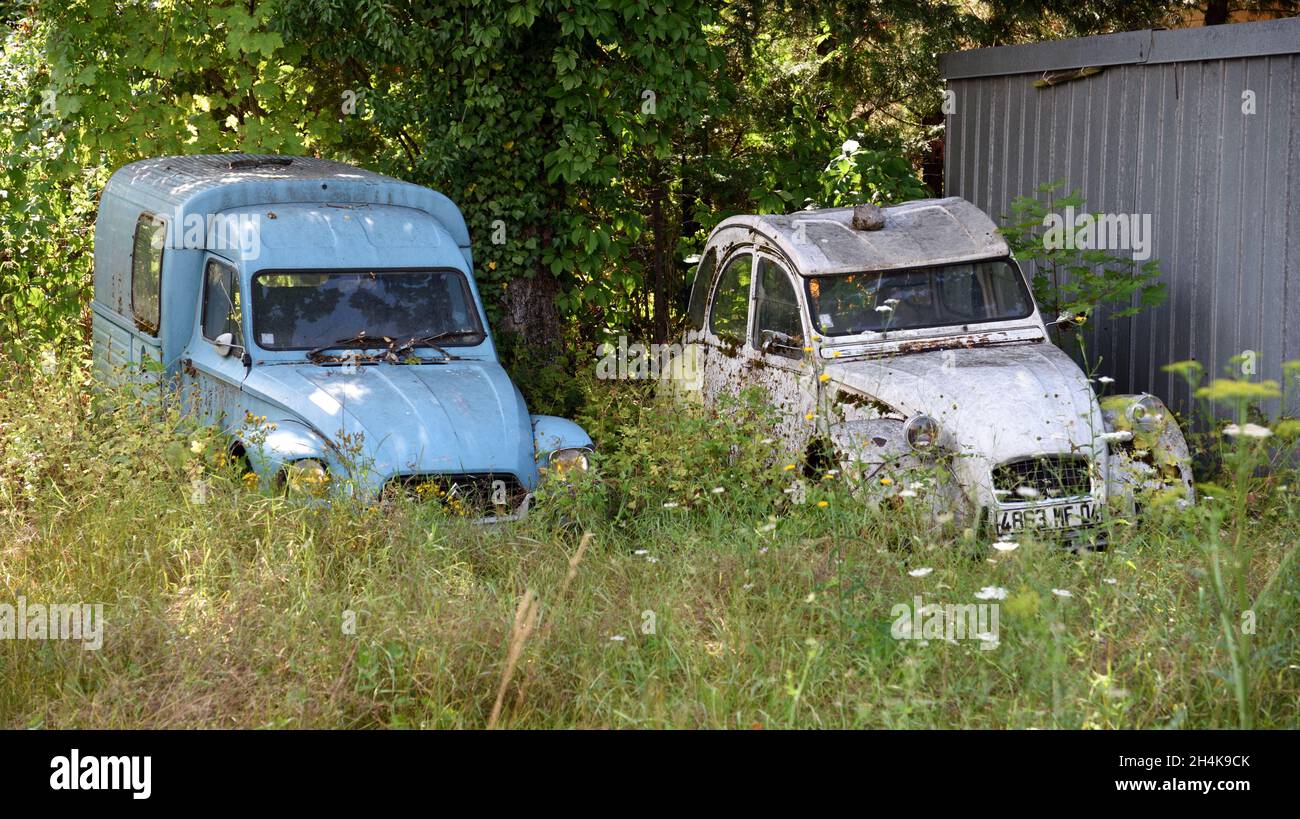 Pair or Couple of Old Vintage or Abandoned Citroën 2CV, or deux chevaux, Cars or Automobiles Abandoned in Back Yard Stock Photo