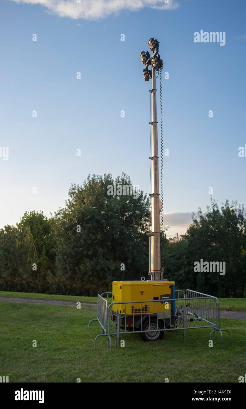 Moble fuel consumption light tower over grass during daylight performance. Sunset blue sky background. Stock Photo