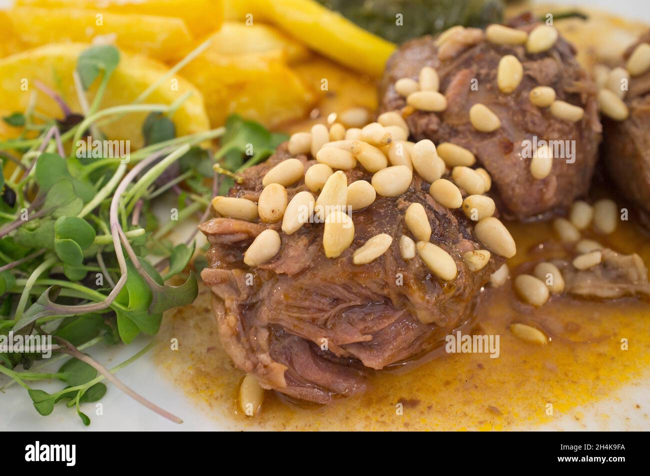 Stew cheek pieces of iberian topped with pine nuts and corn salad. Closeup. Stock Photo