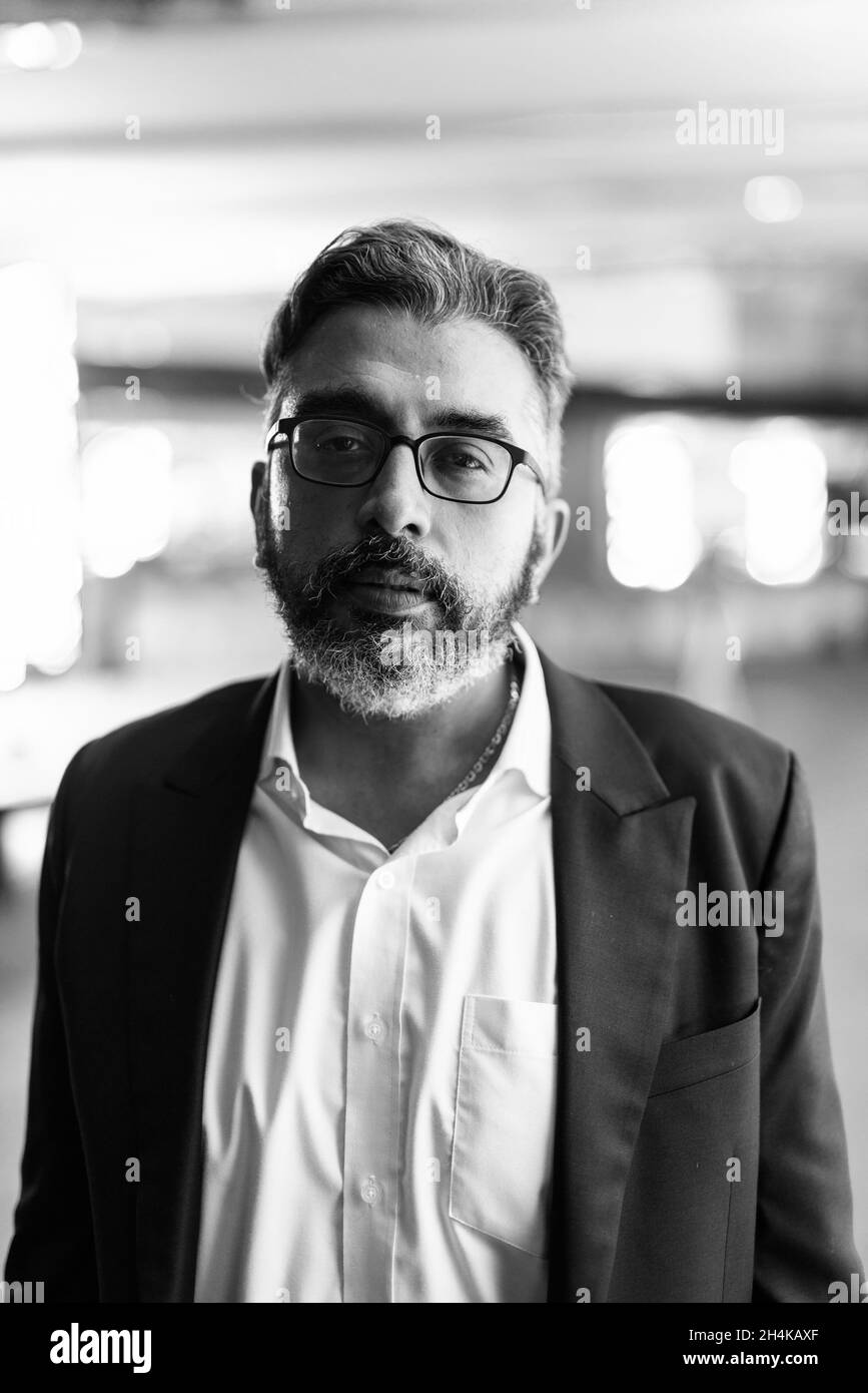 Black and white portrait of handsome Indian businessman in city at night Stock Photo