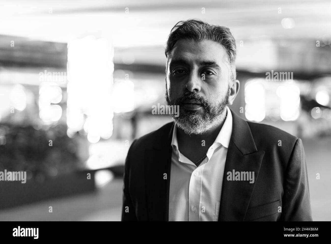 Black and white portrait of handsome Indian businessman in city at night Stock Photo