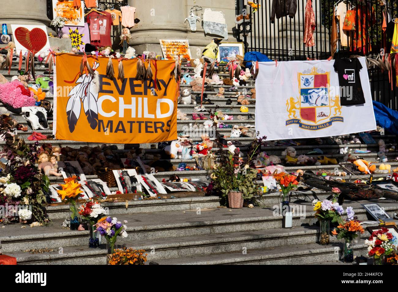 Shoes, toys, flowers are part of a memorial and protest about child victims of Indian Residential Schools in Canada, on the steps at the Vancouver Stock Photo