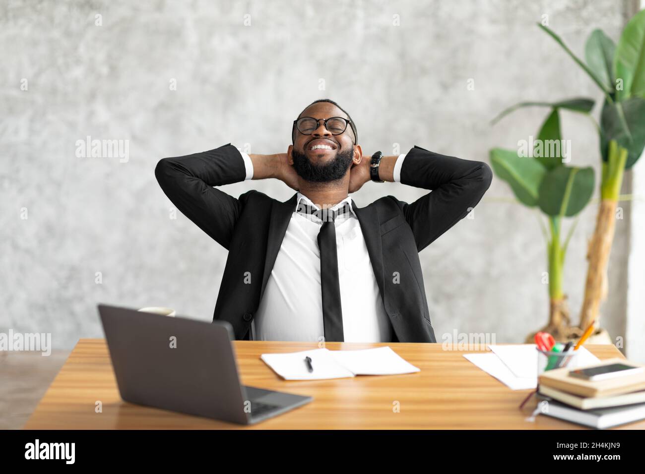 Taking Break. Smiling African company employee leaning back on chair
