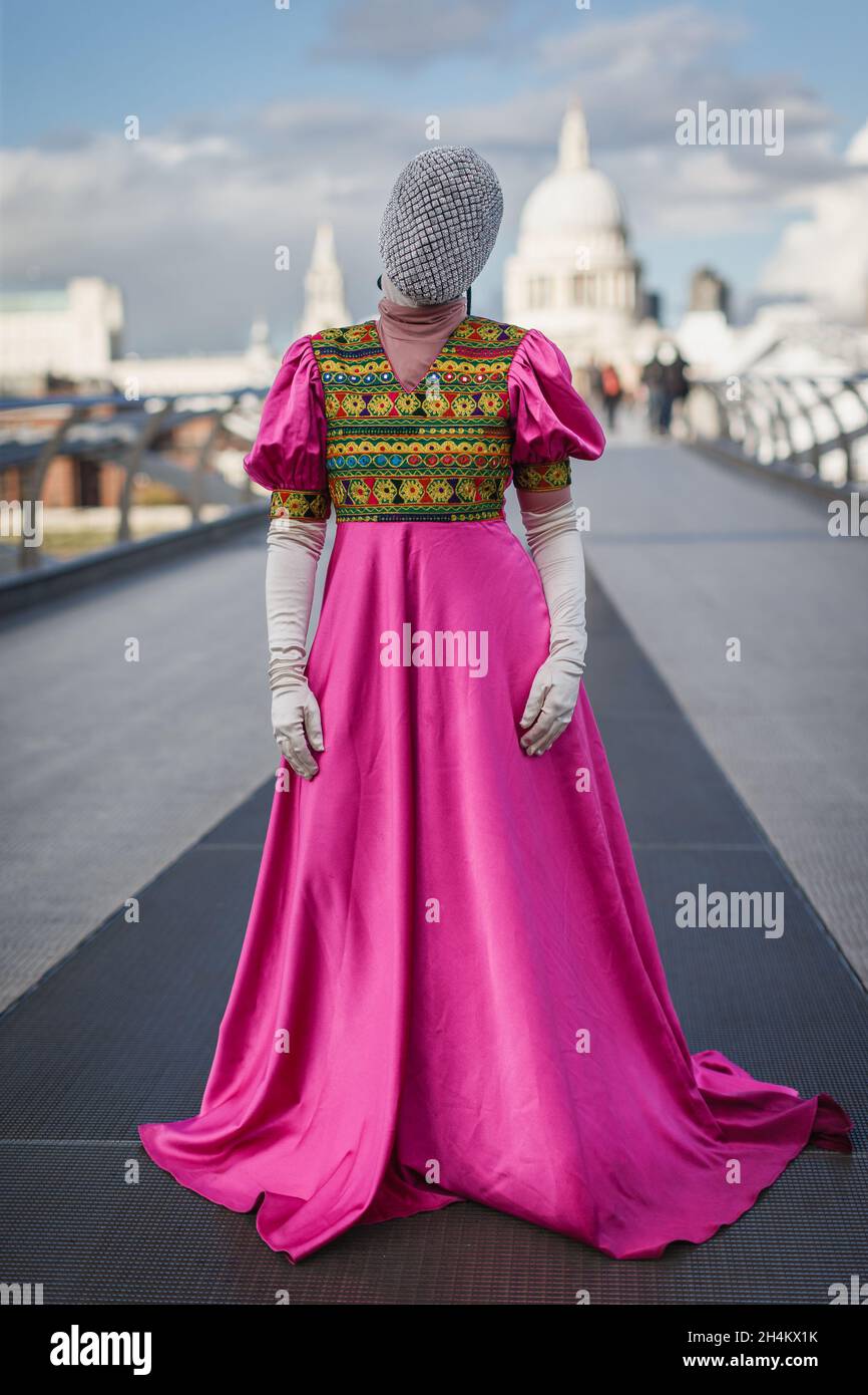 A fully covered afghan woman in a traditional pink dress on Millennium Bridge in London. Stock Photo