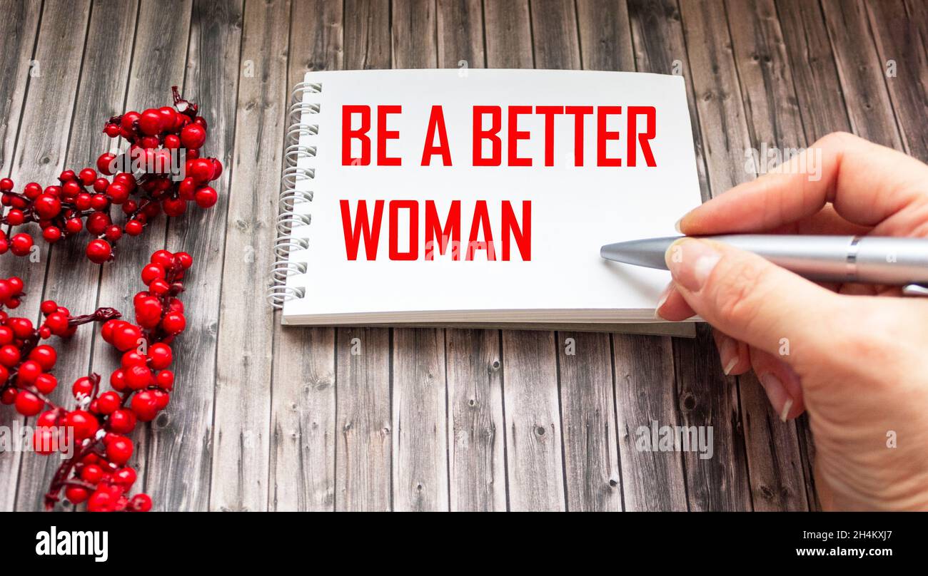 The text Be the Best Woman is written by a woman's hand on a wooden background is a bunch of mountain ash. Stock Photo